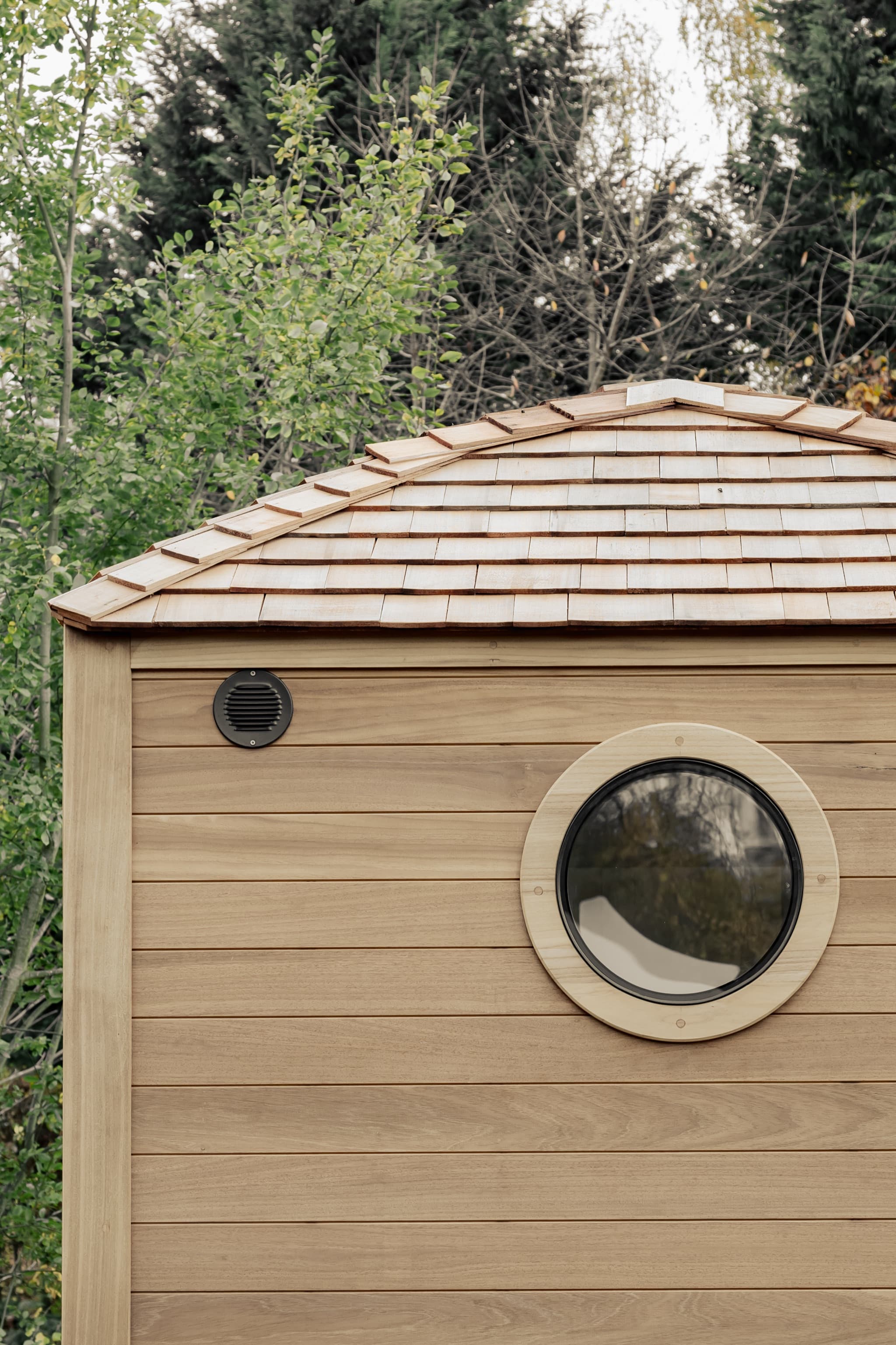 Cedar-shingled Wildernest cabin with a round porthole window